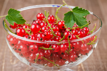 glass bowl full of red currant on a wooden background/glass bowl full of red currant on a wooden background. Close up. Wiht copy space