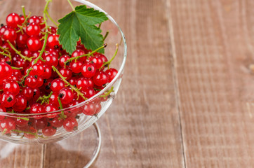 glass bowl full of red currant on a wooden background/glass bowl full of red currant on a wooden background. Wiht copy space