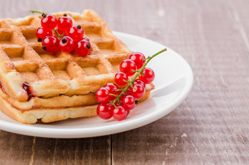 wafers with red berries in a white plate on a wooden background/wafers with red berries in a white plate on a wooden background. Selective focus