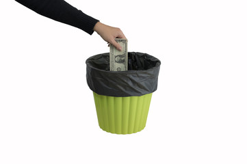 Money concept. Someone hand throwing money into the trash or green bin isolated on white background.