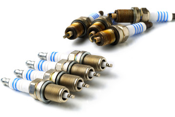 all-new and used spark plugs on white background, copy space