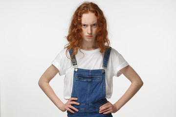 Indoor closeup of young beautiful redhead European lady isolated on white background pressing her...