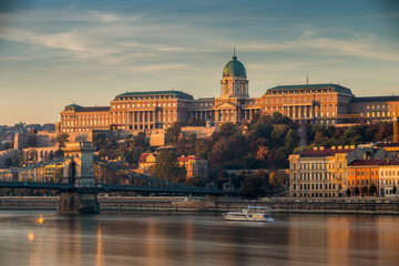 Fototapeta na wymiar Budapest, Hungary - Beautiful golden sunrise at the Buda side with Buda Castle Royal Palace, Szechenyi Chain Bridge and sightseeing boat on River Danube