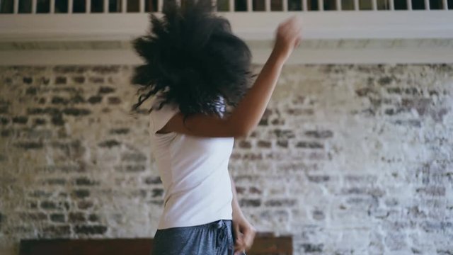 Handheld of joyful african american teeanger girl have fun dancing near bed at home
