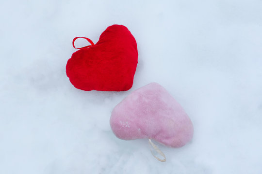 Pink and red plush decorative hearts on snow