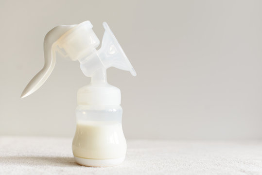 Breast pump with milk for baby over blurred background