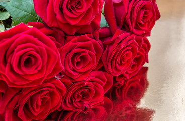 Bunch of red roses on golden reflective background. Close up. Background for greeting card.
