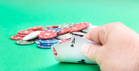 Male hand show pair of aces on the green poker table.