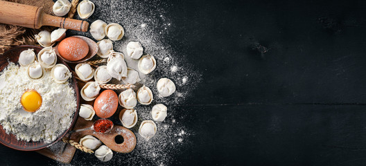 Traditional russian pelmeni, ravioli, dumplings with meat on black concrete background. Top view. Copyspace.