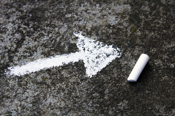  chalk drawing on asphalt: white arrow sign
