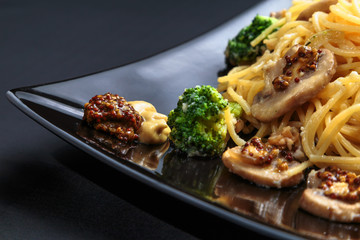 spaghetti with mushrooms and broccoli in a creamy sauce on a dark background