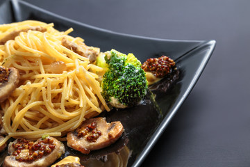 spaghetti with mushrooms and broccoli in a creamy sauce on a dark background