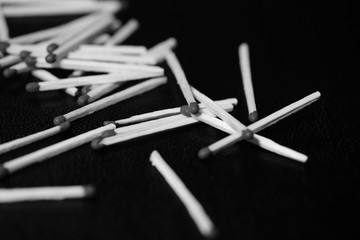 Scattered matches on dark background close up. Black and white