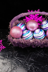 Christmas balls in purple basket on black background. Decorative snowflakes.