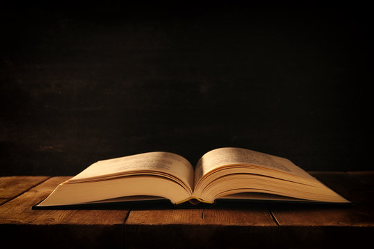 image of open antique book on wooden table