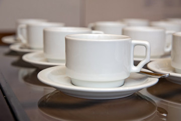 Close up dirty coffee cup and spoon setting on white saucer and wooden table after drinking in the morning in vintage style. cup