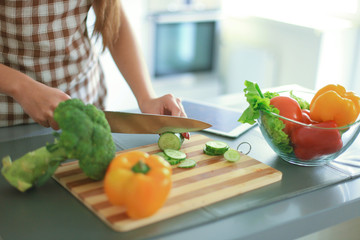 Young woman cutting vegetables in kitchen at home.