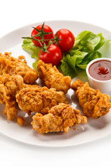 Fried chicken nuggets with vegetables on white background