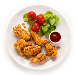 Fried chicken nuggets with vegetables on white background