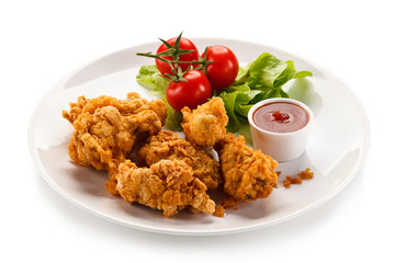 Fried chicken nuggets with vegetables on white background