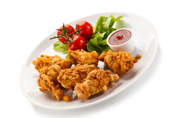 Fried chicken nuggets with vegetables on white background