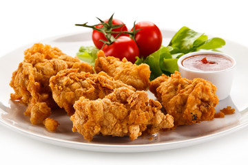 Fried chicken nuggets with vegetables on white background