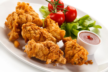 Fried chicken nuggets with vegetables on white background