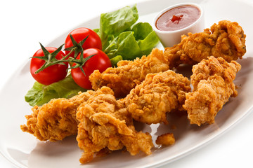 Fried chicken nuggets with vegetables on white background
