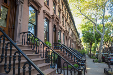 Scenic view of a classic Brooklyn brownstone block with a long facade and ornate stoop balustrades...