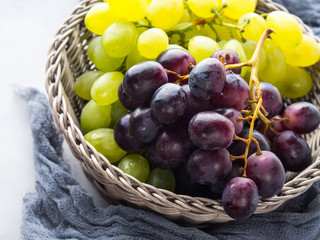 White and dark grapes in a basket on gray. Abstract minimal fruit still life