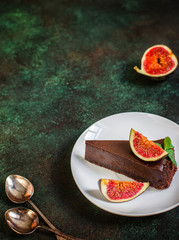 Chocolate cheesecake with fig on green slate background.