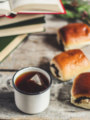 a mug of hot and fragrant tea with buns with a poppy filling  and reading books