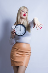 Business portrait of a beautiful young blond woman. A girl is holding a watch and is posing.