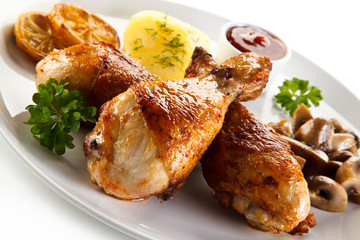 Grilled chicken drumsticks with vegetables on white background