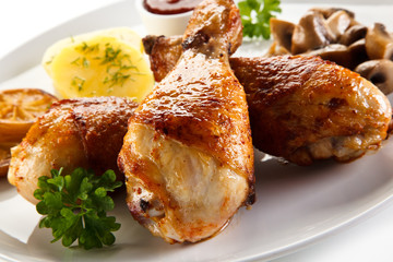 Grilled chicken drumsticks with vegetables on white background