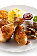 Grilled chicken drumsticks with vegetables on white background
