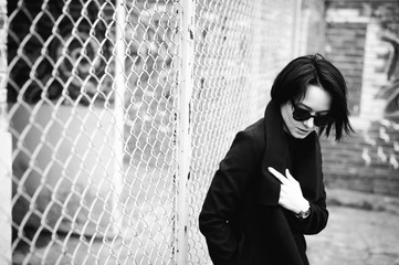 emotional fashionable portrait of a young brunette woman in black clothes, jeans T-shirt, coat and sunglasses, in a Gothic style sad mood.