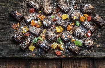 chocolate candies, candied fruits on a wooden background