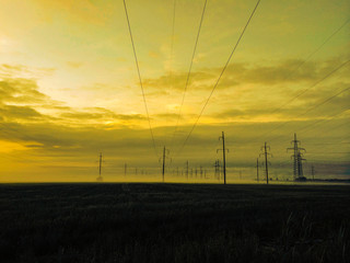Electric power lines in the fog. Morning dawn in the dense heavy mist.