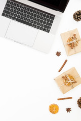 Laptop and Christmas gift box, cinnamon and cones on white background. Top view. Flat lay. Holiday concept