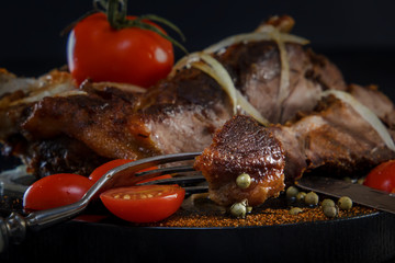 Fried lamb with vegetables. Fried meat on a black background. BBQ. Closeup. Piece of meat on the fork