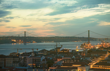 Alfama downtown and the 25 April Bridge in Lisbon at evening.