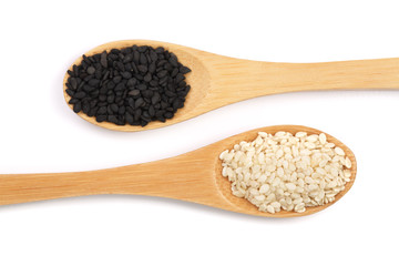 Black and white sesame seeds in a wooden spoon isolated on white background top view