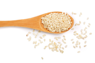 Sesame seeds in a wooden spoon isolated on white background top view