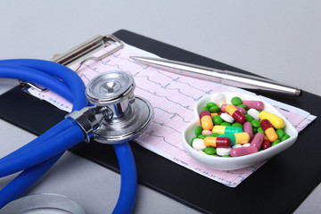 Stethoscope, RX prescription and colorful assortment pills and capsules on plate.
