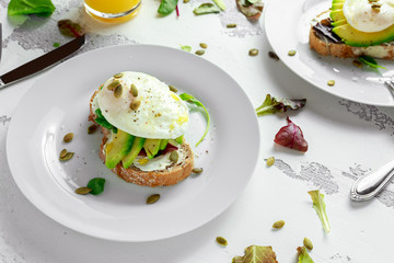 Sandwich, toast with avocado, soft cheese and poached egg on white background