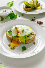 Sandwich, toast with avocado, soft cheese and poached egg on white background