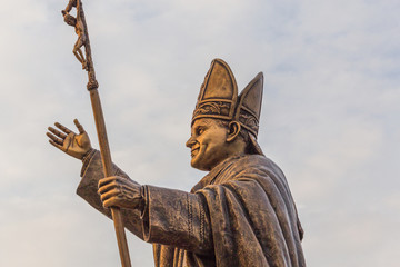 Ancient brass sculpture of Pope, the bishop of Rome with golden sunlight glare on the statue.