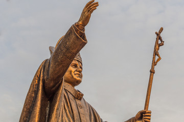 Ancient brass sculpture of Pope, the bishop of Rome with golden sunlight glare on the statue. With selective focus on the subject.