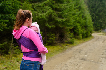 Mom with baby in sling for a walk in the woods